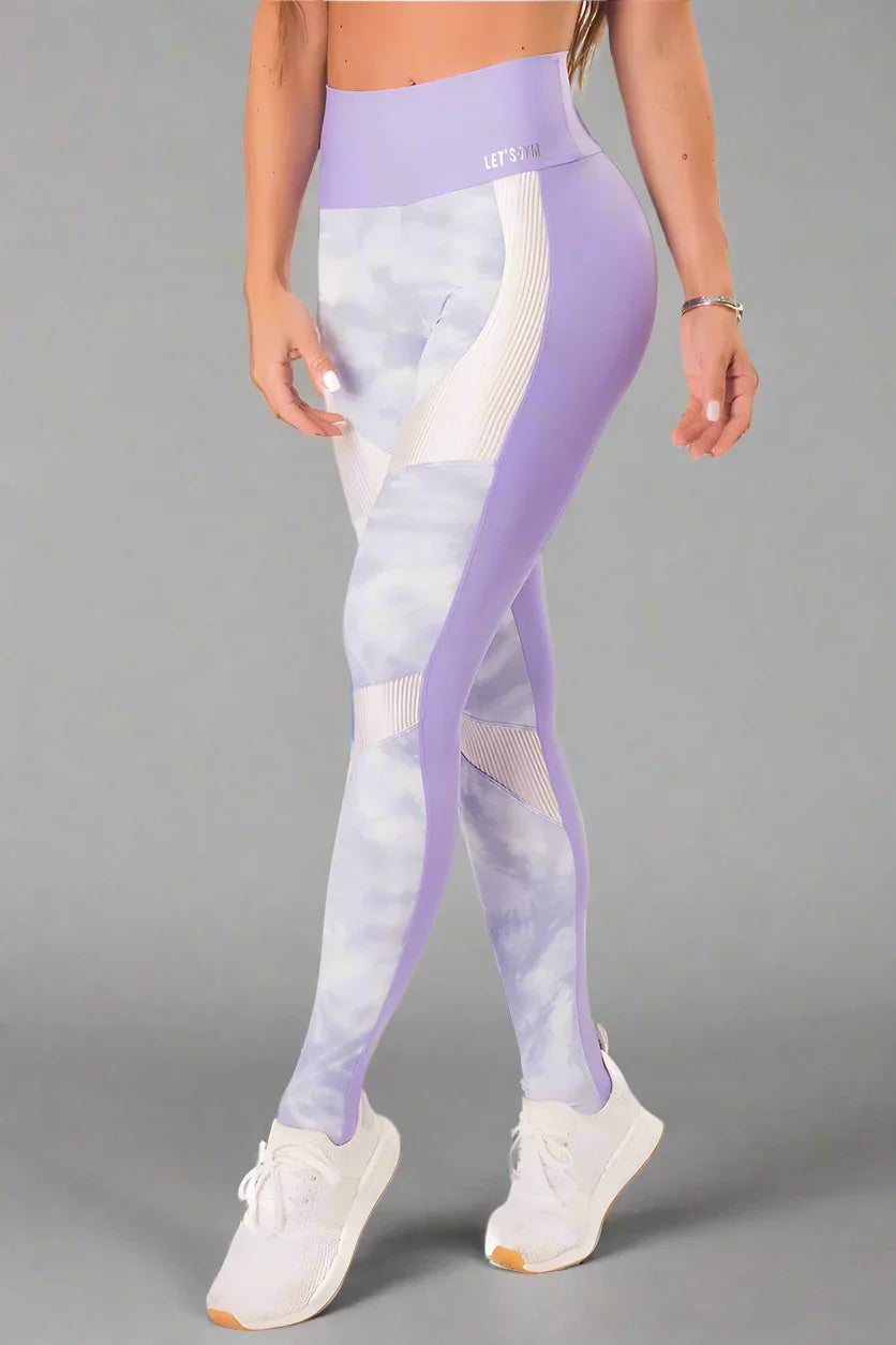 A pair of workout leggings with a high waist, featuring a lilac print on the front and a solid purple color on the back, with white ribbed trim at the waist.