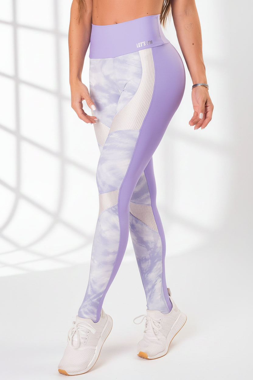 A pair of workout leggings with a high waist, featuring a lilac print on the front and a solid purple color on the back, with white ribbed trim at the waist.