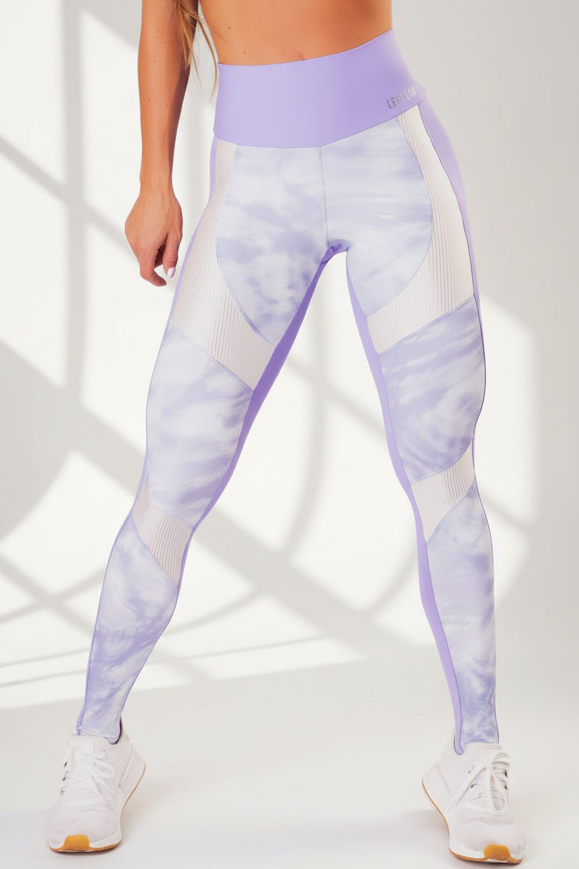 A pair of workout leggings with a high waist, featuring a lilac print on the front and a solid purple color on the back, with white ribbed trim at the waist.