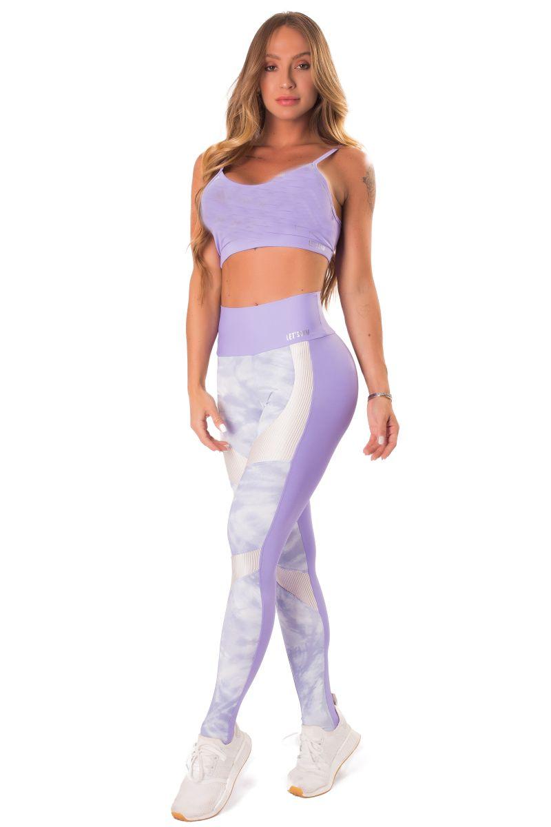 A pair of workout leggings with a high waist, featuring a lilac print on the front and a solid purple color on the back, with white ribbed trim at the waist.