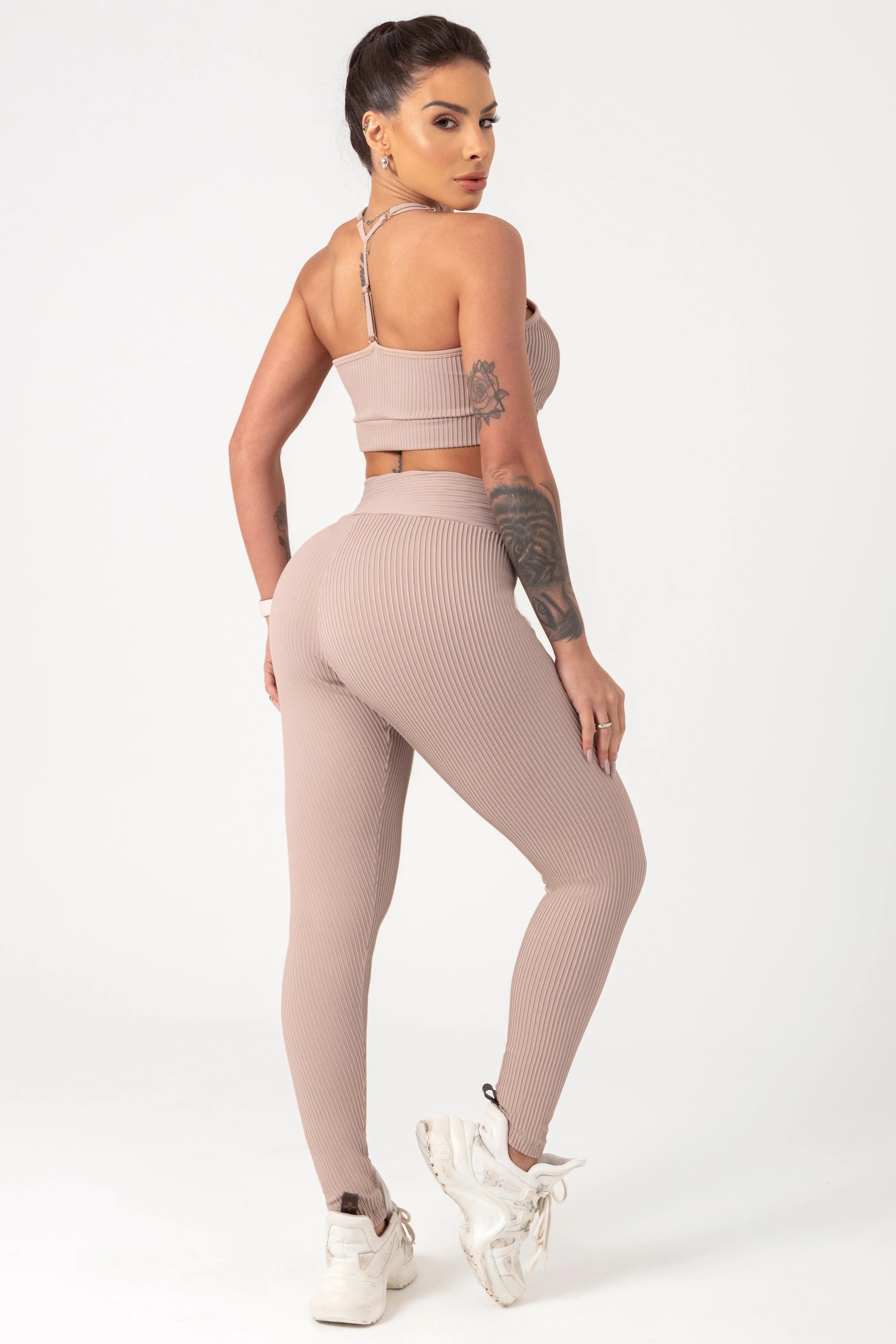 back view of tan leggings and bra top. Model looking over her shoulder