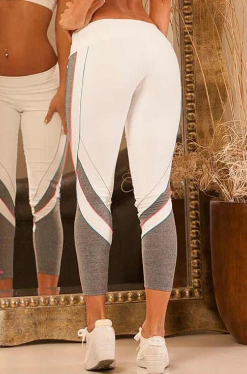 A person wearing Alto Giro Glacier Legging with white as the primary color, featuring contrasting gray panels and turquoise & neon coral piping.
