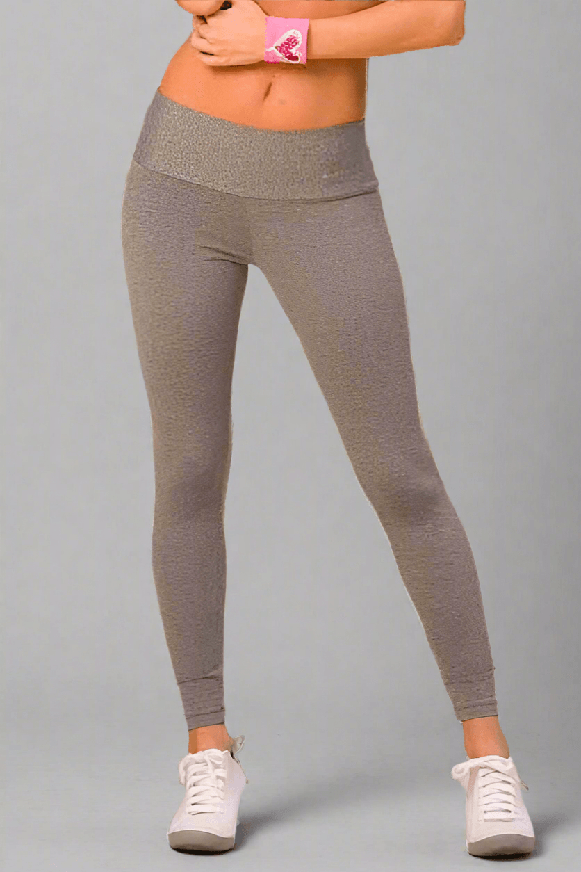 A pair of heather gray Alto Giro workout leggings with a thick waistband, worn with white sneakers and a pink wristband