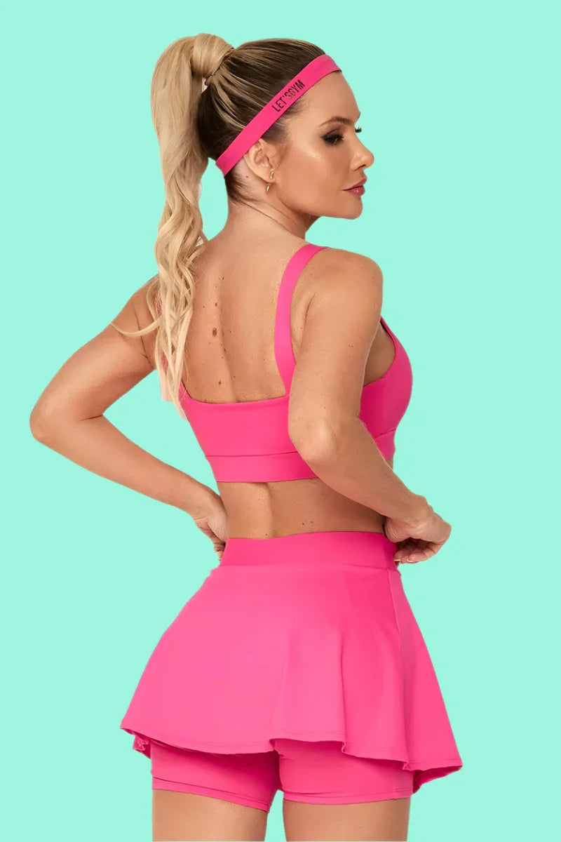 Woman wearing a pink sports outfit with a headband on a teal background