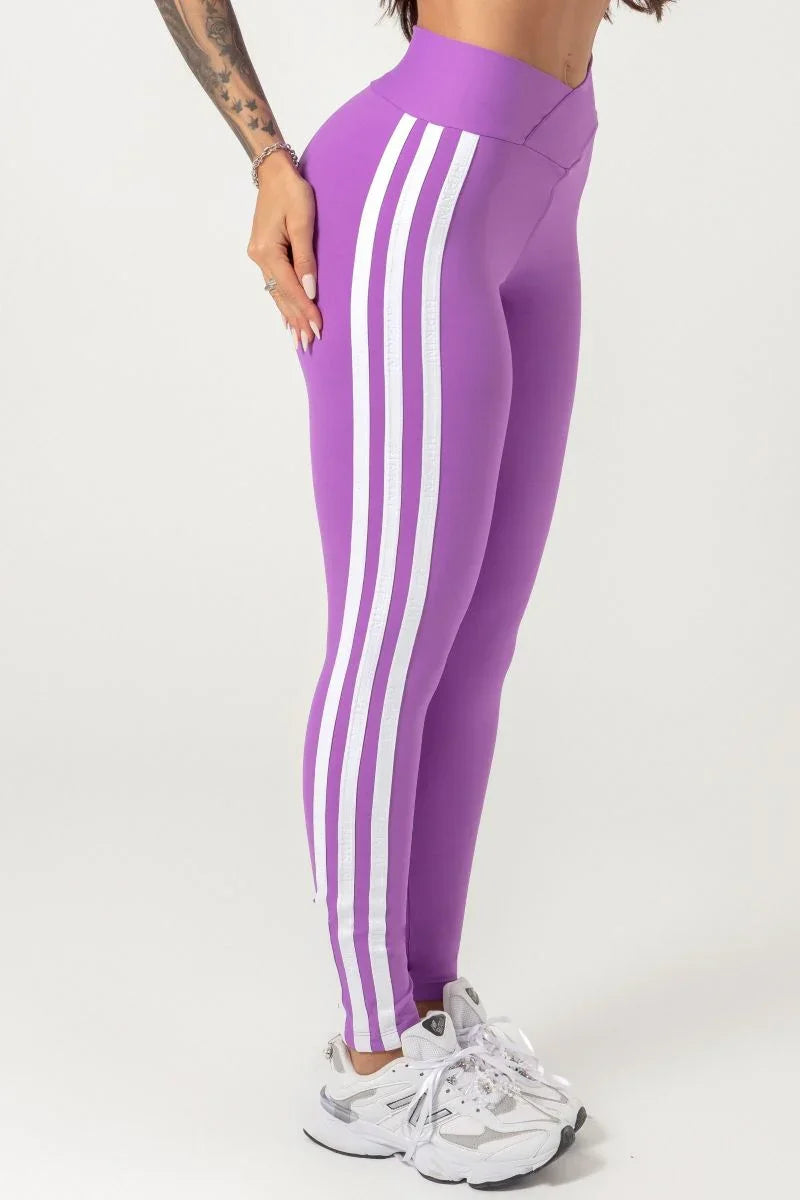 A person wearing a purple Hipkini Victory V Front Legging with white side striping, paired with a white top and white sneakers.