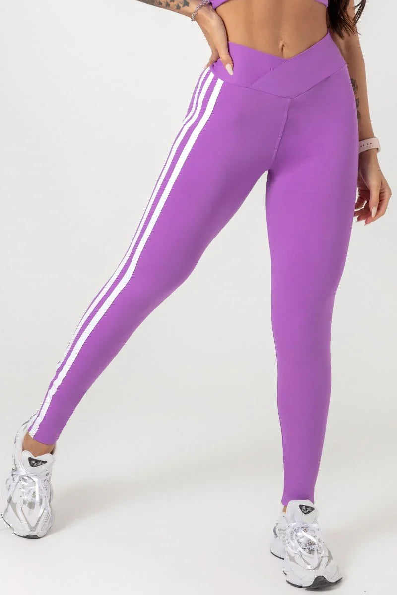 A model wearing a purple Hipkini Victory V Front Legging with white side striping and high-waisted.