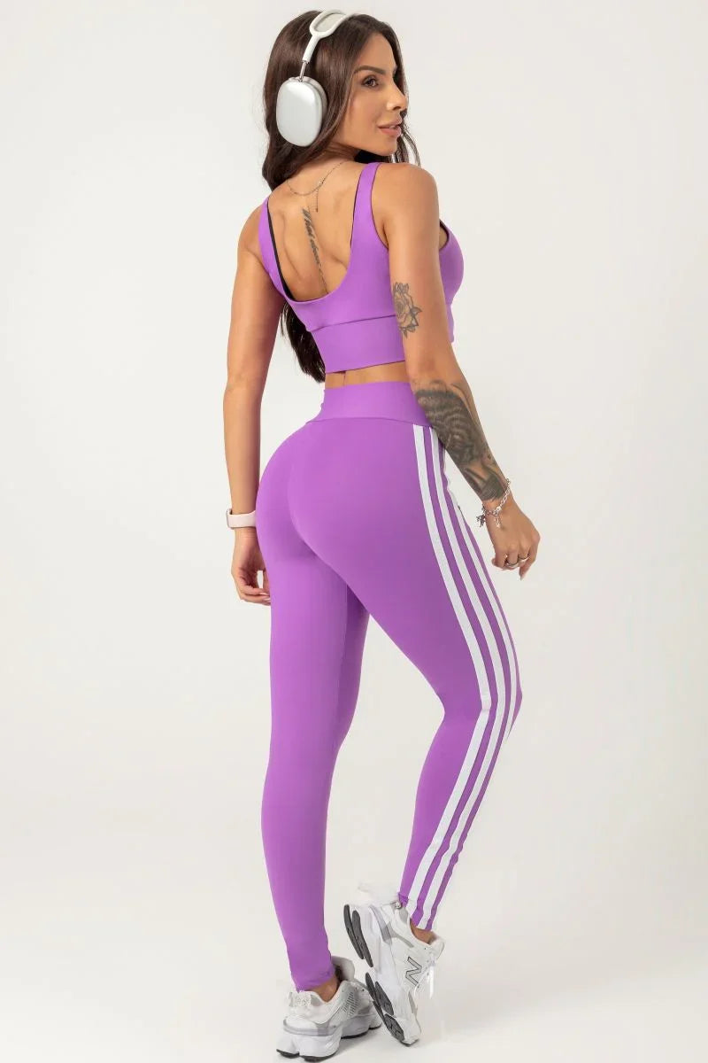 back view of a A person wearing a purple Hipkini Victory V Front Legging with white side striping, paired with a white top and white sneakers.