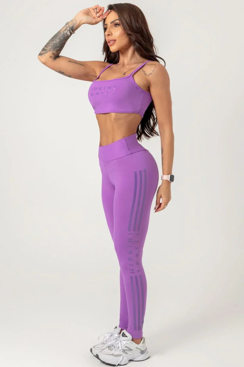 Side view of a Woman wearing a purple athletic outfit on a white background