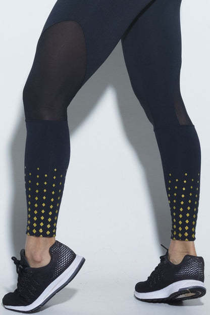 close up of a Person wearing black leggings with mesh panels and small gold diamonds at the ankle on a white background