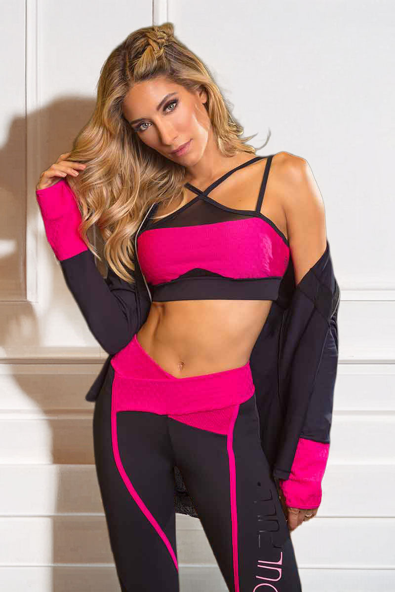 Woman wearing a black and pink athletic outfit against a white wall.